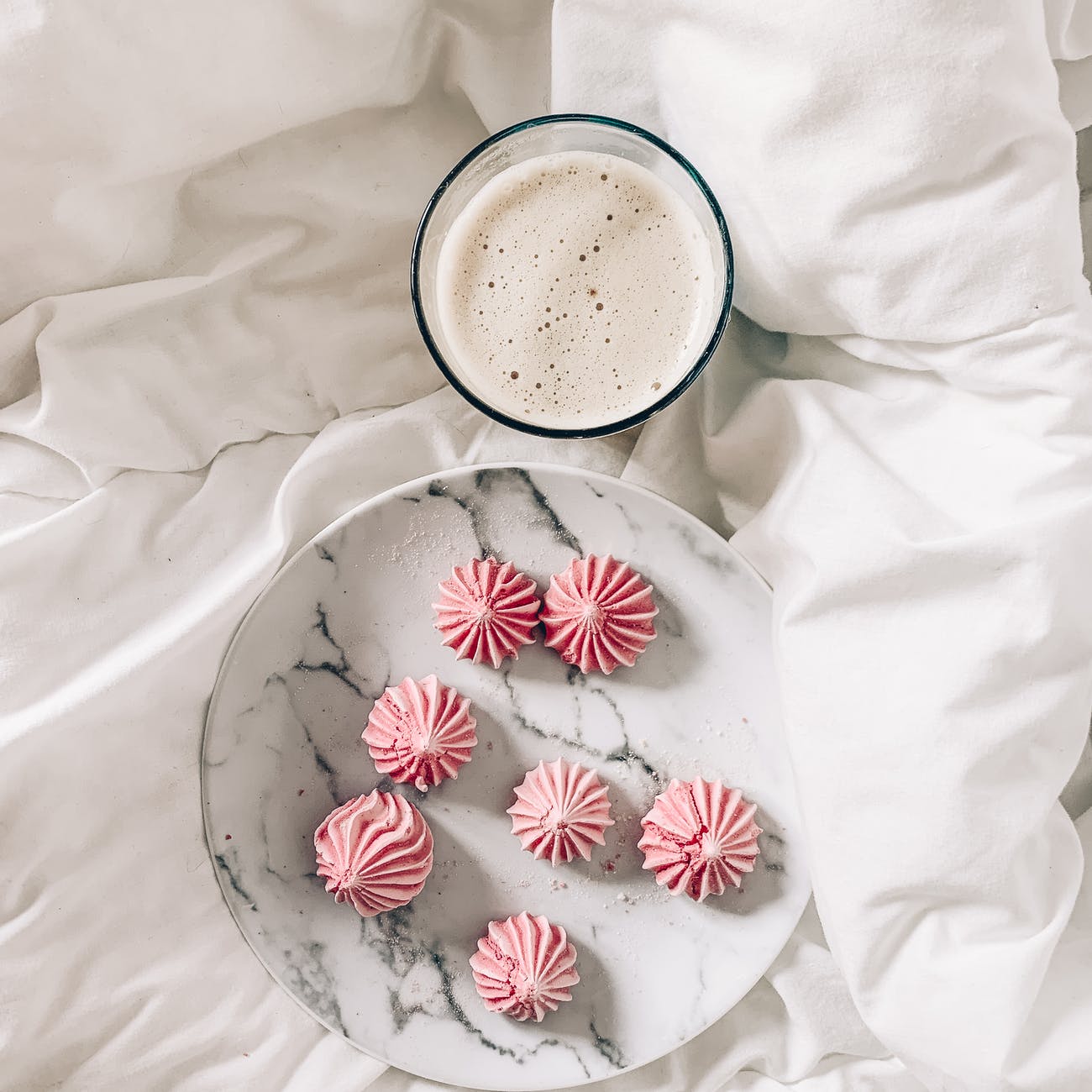 delicious meringues with latte on crumpled bed sheet for breakfast