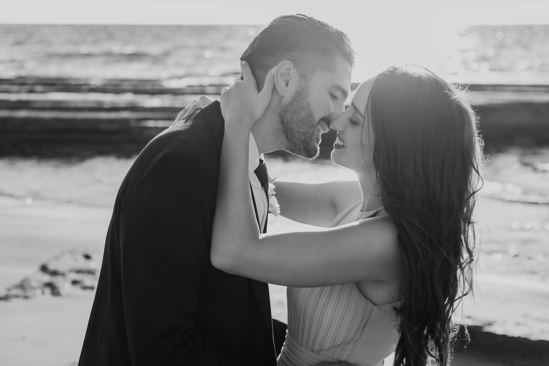 elegantly dressed couple kissing on the beach