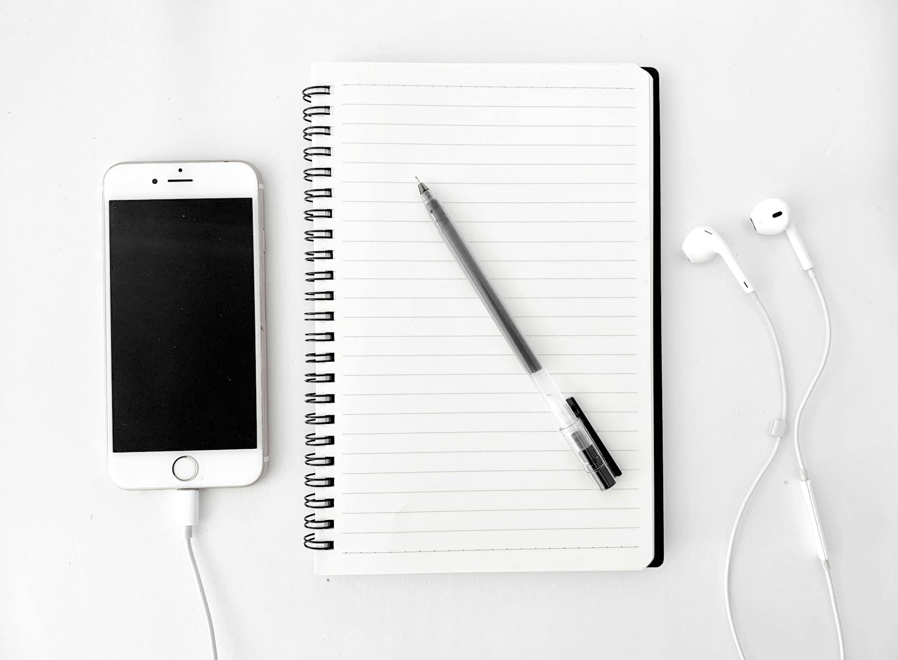 composition of notebook with pen near smartphone