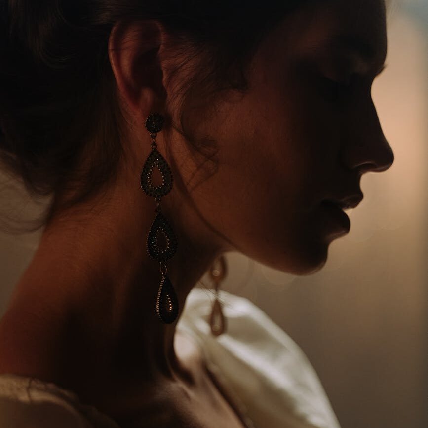 dark feminine woman in white shirt wearing silver necklace